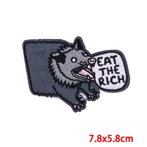 Detail of embroidered opossum patch with Eat the Rich text and iron-on backing, 7.8x5.8cm