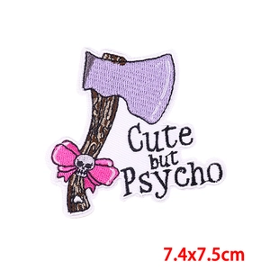 Close-up of 'Cute but Psycho' axe embroidery patch with pink bow detail and size info