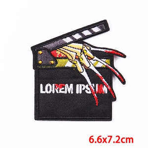 Macro shot of punk horror movie clapperboard embroidery patch with metallic claw detail