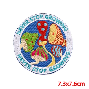 Detail of embroidered mushroom patch with Never Stop Growing text on dark blue background