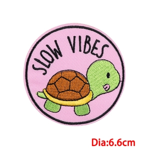 Detail of 6.6cm round cartoon turtle patch with Slow Vibes embroidery and pink border