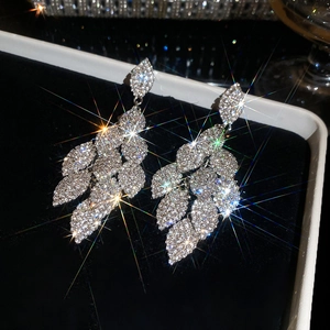 Detailed macro view of silver needle earrings with shimmering leaf-shaped rhinestones.