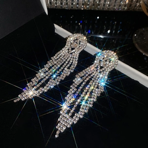 Detailed close-up showing the shimmering rhinestones of long tassel earrings on black velvet