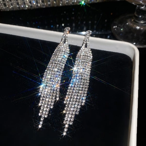 Close-up of sparkling rhinestone fringe earrings displayed on premium black velvet lining