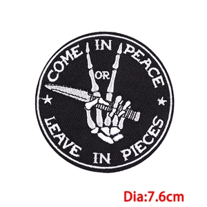 Detail of round punk skeleton embroidery patch with Come in peace or leave in pieces slogan