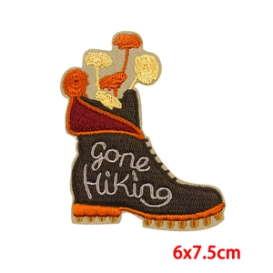 Detail of embroidered Gone Hiking boot patch with yellow flowers and white script