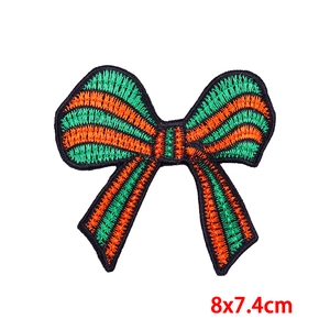 Detailed close-up of a striped 8x7.4cm orange and green bow embroidered iron-on patch