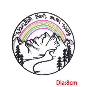 Macro detail of an 8cm round embroidered mountain patch with Wander your own way text