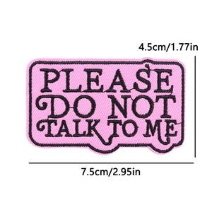Macro view of pink embroidered patch with Please Do Not Talk To Me text and 7.5cm dimensions
