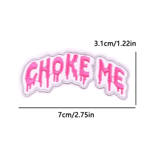 Macro shot of pink CHOKE ME embroidered patch with silver edge and 7x3.1cm dimensions