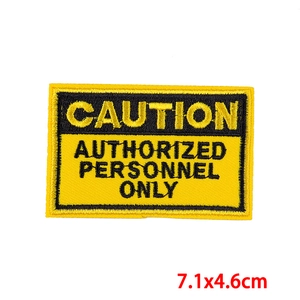 Macro detail of Caution Authorized Personnel Only embroidered patch with yellow border