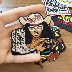 Detalle de parche bordado de mujer africana con sombrero de vaquero y botas en madera