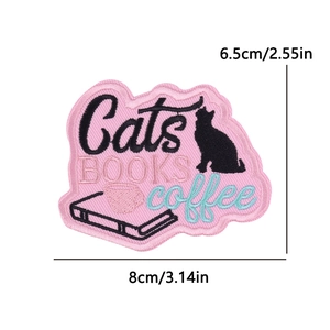 Detailed view of pink embroidered patch with black cat silhouette, books and coffee