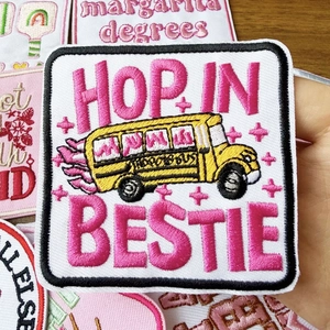 Macro shot of embroidered school bus patch with pink Hop In Bestie lettering