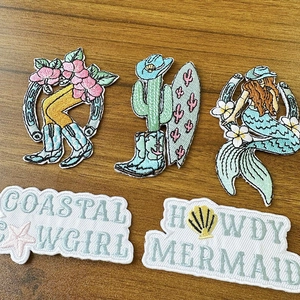 Detailed embroidery texture of coastal cowgirl and mermaid theme patches for DIY projects