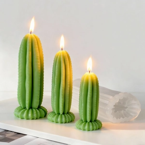 Three green cactus candles with warm flames and a silicone mold on a white background