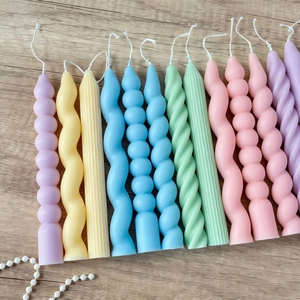 Flat lay of colorful ribbed and spiral decorative scented candles on wood surface