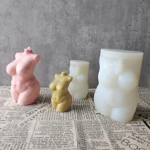 Detailed view of female torso silicone molds and finished art candles in pink and tan
