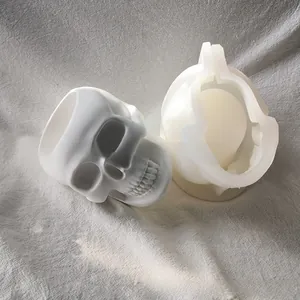 Detailed view of white silicone skull mold next to finished resin plaster craft piece