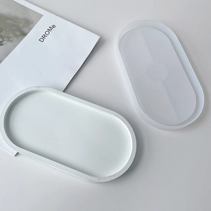 Oval silicone mold and finished white resin tray on a minimalist modern white surface