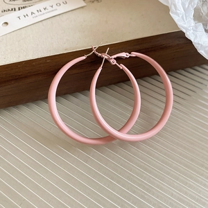 Close-up macro view of matte pink C-shaped hoop earrings featuring high quality silver needles