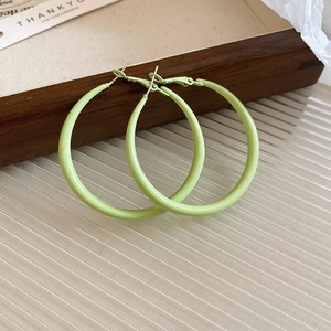 Macro detail of minimalist retro light green matte hoop earrings with silver needle studs