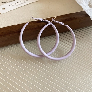 Macro view of minimalist matte lavender purple C-shaped hoop earrings with silver needles
