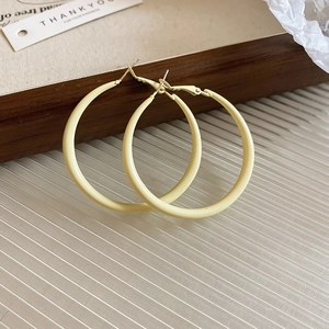 Detailed view of pale yellow C-shaped hoop earrings on a minimalist wooden tray