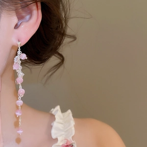 Detailopname van elegante lange kwastjes oorbellen met roze kattenoogstenen en zirkoon