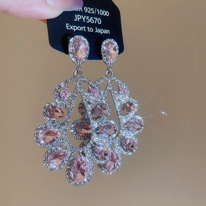 Close-up view of vintage fan-shaped tassel earrings featuring pink teardrop zircons