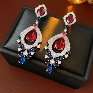 Close-up of vintage tassel earrings with colorful zircons on a black jewelry box.