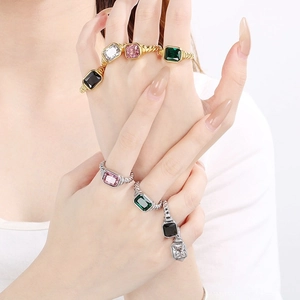 Elegant twisted border square glass rings in multiple colors on a model's hand.