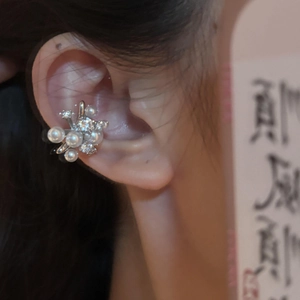 Vista dettagliata di un elegante ear cuff a forma di fiore con perle e zirconi sull'orecchio.