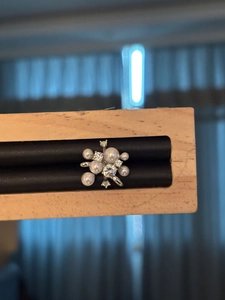 Dettaglio dell'orecchino a clip fiore perla zircone su supporto in legno