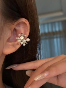 Dettaglio di un elegante ear cuff a fiore con perle e pietre di zircone luminose.