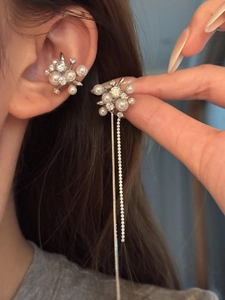 Dettaglio del ear cuff a fiore in argento con perle e nappe di zirconi per donne.