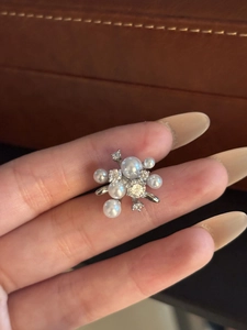 Dettaglio ravvicinato di un ear cuff floreale argento con perle bianche e zirconi lucidi