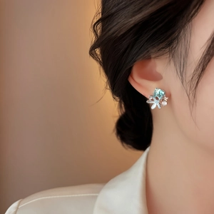 Detail shot of elegant starfish stud earrings with light blue crystal on model's ear