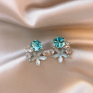 Close-up of blue starfish stud earrings with crystals on champagne silk background.