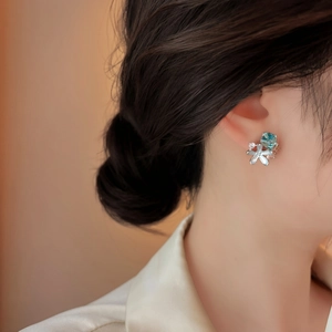 Close-up of elegant flower stud earrings with blue stone on female ear