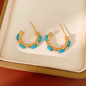 Detail view of vintage C-shaped gold stud earrings with turquoise and zircon stones