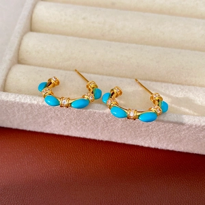 Detailed macro shot of vintage C-shape earrings with turquoise stones and gold plating