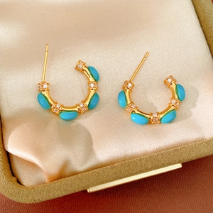 Detail of vintage gold-plated C-shaped earrings with turquoise and zircons