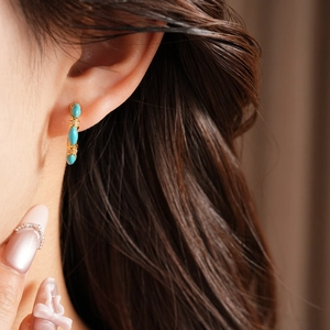 Close-up of vintage C-shaped gold-plated earring with blue stones and zircons