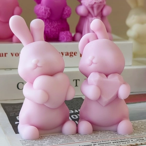 Detail view of two cute pink bunny candles holding hearts for DIY Valentine crafts