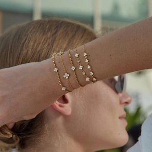 Macro detail of elegant gold-plated stainless steel clover bracelets with white zircons