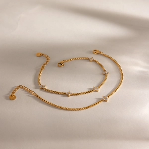 Detailed macro shot of two elegant gold stainless steel clover bracelets with white zircons
