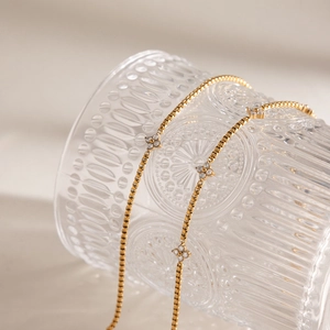Detail of gold box chain bracelet featuring zircon-studded clover charms for women.