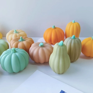 Detailed view of pumpkin shaped candles in assorted pastel colors and matte textures