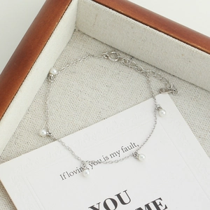 Détail rapproché d'un délicat bracelet en argent sterling S925 aux perles blanches